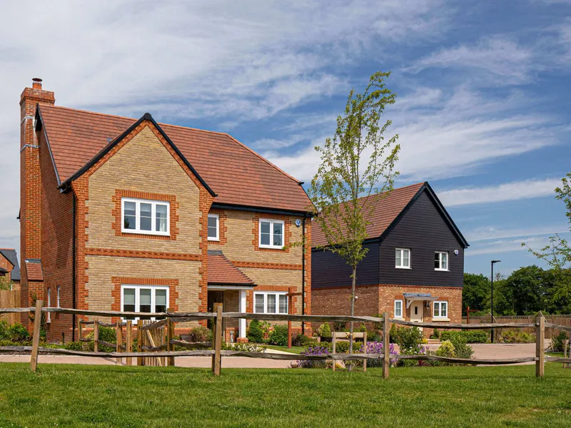 Detached brick houses along a new street with fences and planting