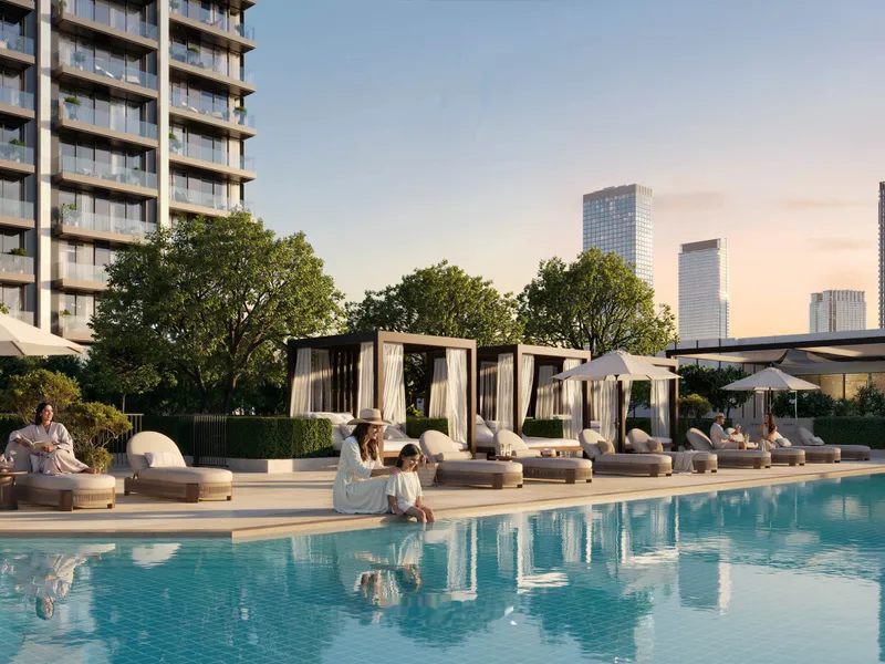 Pool deck at dusk with loungers, cabanas and the skyline behind
